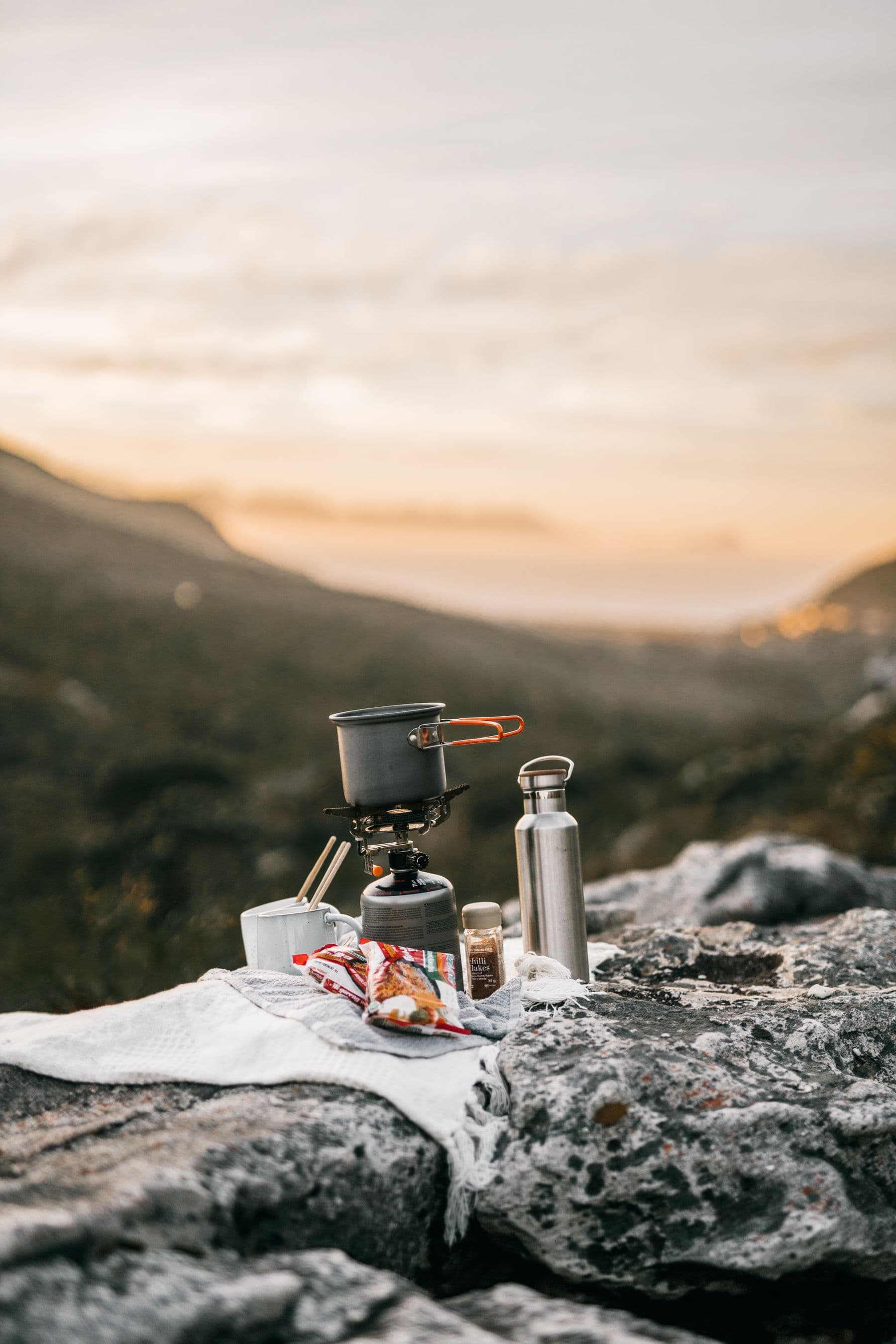 A camp stove and kettle overlooking the mountains at sunrise